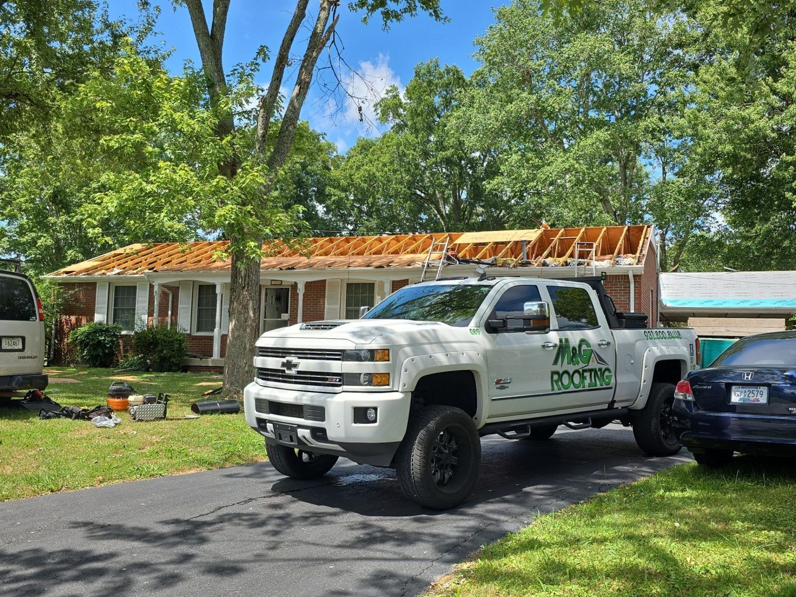 M&G Roofing truck parked at a job with new roof framing